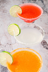 two classic and strawberry margarita, white and red alcoholic cocktail with decoration of salt on the edge of the glass with fresh lime, lemon, daiquiri on gray background restaurant. Bar alcohol menu