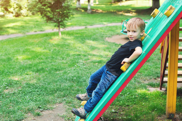 Cute blond boy at playground outdoors.