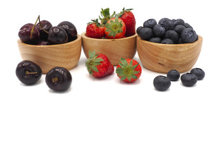 Fresh summer fruits, Cherry, strawberry, and blueberry in wooden bowl isolated on white background.