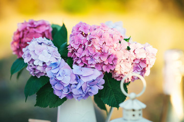 Pretty bouquet of hydrangea flowers in a vintage jar. Flower decor on the garden table.