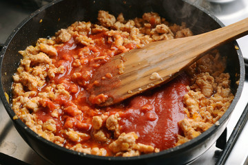 Fried chicken forcemeat with tomato sauce in a pan.
