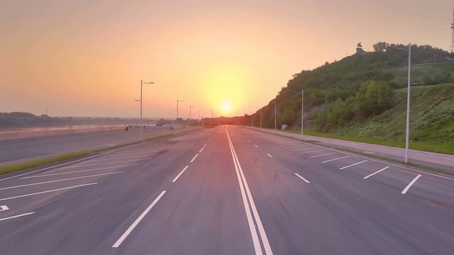 AERIAL: New asphalt road on the embankment of the river Ufa. Beautiful sunset landscape of the river and the city of Ufa.