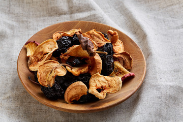 Close-up wooden bowl with dried fruits on a light tablecloth