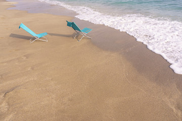 Fototapeta na wymiar Two sun loungers on the sandy beach