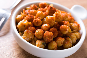 Fried spicy chickpeas on wooden table