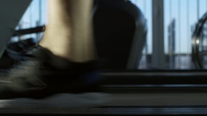 Close up feet of man walking at brisk pace on treadmill at the gym, tracking left