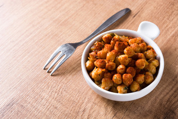 Fried spicy chickpeas on wooden table