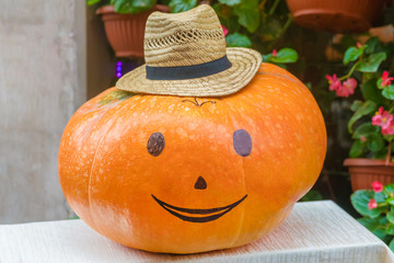 Halloween pumpkin with painted face in a straw hat