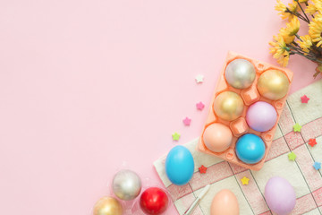 Flat lay top view colorful easter egg painted in pastel colors composition and spring flowers on pink pastel color background. Easter day background top view with copy space.