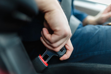 Men's hand fastens the seat belt of the car. Close your car seat belt while sitting inside the car...