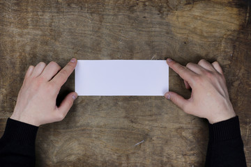 male hands holding a white blank sheet of paper