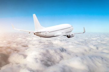 Passenger airplane fly on a hight above clouds and blue sky.