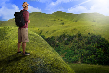 Rear view of asian backpacker standing on the hill peak