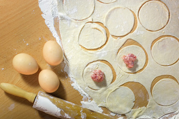 Dumplings raw on a wooden board. The process of cooking dumplings.