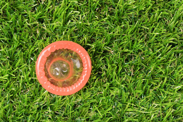 Red condom on the green gras in the nature