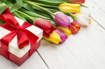 bouquet of tulips with a gift on rustic wooden board