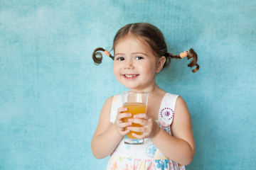Smiling girl with funny pigtails with glass of juice