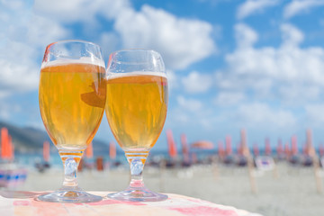 Two glass glasses with beer on the beach