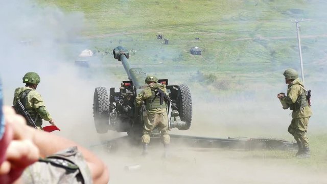 Soldiers are firing the enemy from a large ground cannon at the exercises