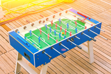 Football table on a wooden plank floor in the sunlight