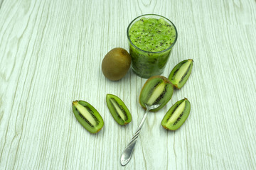Healthy fresh kiwi smoothie in glass on a wooden background .