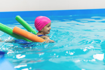A little girl of European appearance floating in the pool on inflatable toy