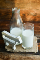 milk bottle, glass of milk, a figure of a cow the concept of a village power, farm-fresh products on a natural wooden background