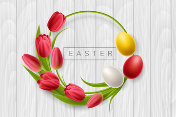 Round Easter frame from red tulip flowers and colorful Easter eggs. Circle frame on white wood texture for spring and Easter holiday design