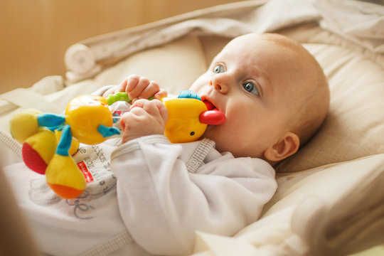 a small child lies and plays with a toy. baby with a toy in his mouth
