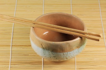 Japanese traditional cup with sticks on vegetable mat.