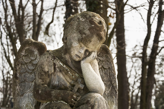 An old stone statue.  An angel cries over the child's grave (religion, Christianity, faith concept)