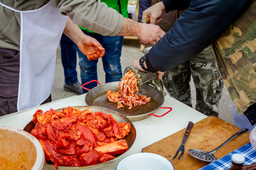 People are mincing meat for handmade sausages at outdoor kitchen