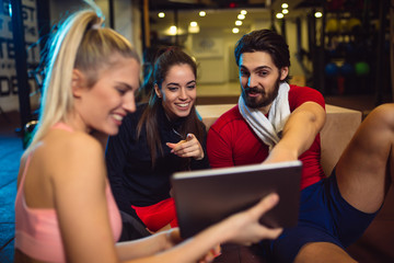 Happy friends using digital tablet in health club