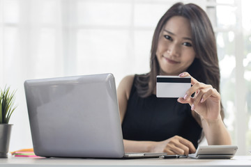 online shopping banner, women looking for buying goods in website on laptop and paying with credit casd on table at home.