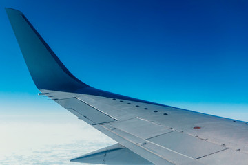 Look at the beautiful wing of the aircraft high in the air above the ground while admiring the blue sky