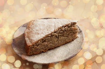 Banana pie with powdered sugar on a plate. Bokeh lights around. Festive dish.