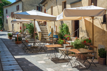 Fototapeta na wymiar Cafe tables and chairs in a street in the village of Bagno Vignoni, Tuscany, Italy
