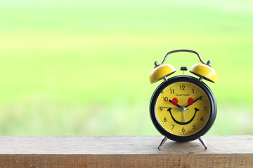 Alarm clock on wooden table with nature background