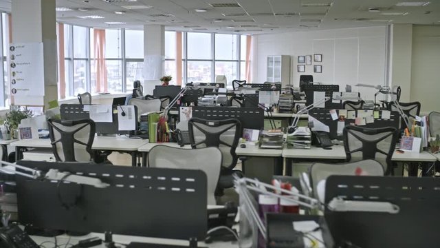 Tracking shot of big empty office with large windows and office-related things on tables, shot in daytime