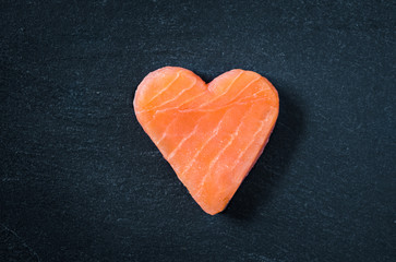 Obraz na płótnie Canvas Salmon copy space black slate background. Heart shaped salmon steak.
