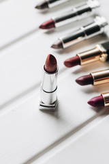 Lipsticks of different colors on wooden background