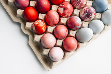 Colorful painted Easter eggs in egg carton, festive background