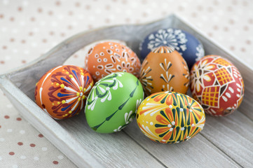 Group of wax painted Easter eggs on light grey tray