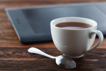 A cup of tea with laptop on the wooden table, shallow depth of field, selective focus