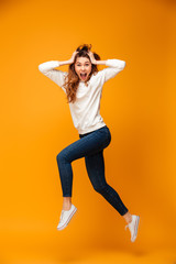 Fototapeta na wymiar Full length image of Shocked brunette woman in sweater jumping