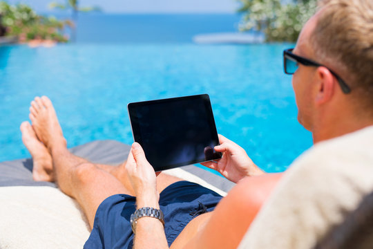 Man holding tablet in hands while on vacation in resort.