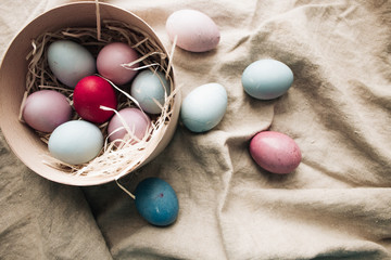 Nest with painted Easter eggs in box on sackcloth, rustic festive composition