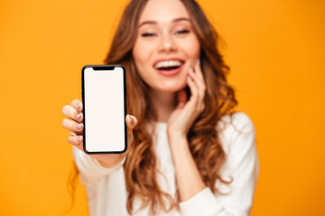 Pleased brunette woman in sweater showing blank smartphone screen
