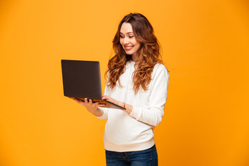 Image of Smiling brunette woman in sweater using laptop computer