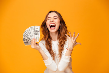 Screaming happy brunette woman in sweater holding money and rejoices